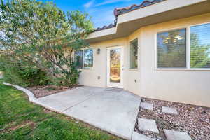 View of exterior entry with a patio area and stucco siding