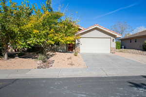 View of front of house featuring concrete driveway, stucco siding, stone siding, a garage, and a tiled roof