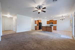 Unfurnished living room featuring light tile patterned flooring, light carpet, a ceiling fan, a chandelier, and recessed lighting