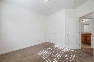 Unfurnished bedroom featuring carpet and ensuite bath