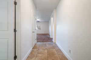 Corridor with baseboards and light tile patterned floors