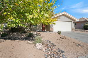 View of front facade with stucco siding, driveway, stone siding, and an attached garage