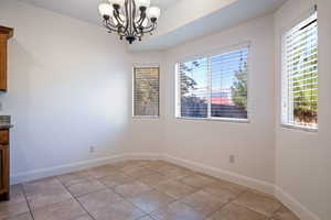 Unfurnished dining area featuring light tile patterned flooring and a chandelier