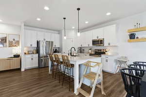 Kitchen featuring stainless steel appliances, white cabinetry, pendant lighting, an island with sink, and recessed lighting