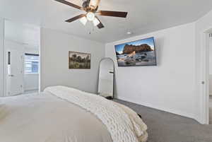 Bedroom with carpet flooring, a ceiling fan, and a textured ceiling