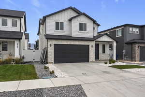 View of front facade with stone siding, board and batten siding, concrete driveway, a gate, and a garage