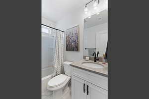 Full bathroom with shower / bathtub combination with curtain, vanity, and light marble finish flooring