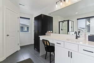 Bathroom with a shower stall, vanity, plenty of natural light, and dark tile patterned flooring