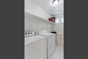 Washroom featuring light marble finish flooring and washing machine and dryer