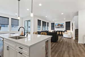 Kitchen with a kitchen bar, white cabinets, light stone counters, decorative light fixtures, and dark wood-style floors