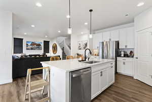 Kitchen featuring decorative light fixtures, stainless steel appliances, white cabinetry, dark wood-style floors, and recessed lighting