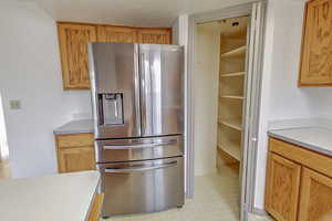 Kitchen with stainless steel fridge with ice dispenser, light floors, light countertops, and a textured ceiling