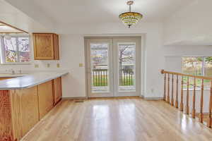 Kitchen with light countertops, plenty of natural light, light wood-style floors, and a peninsula