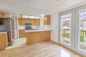 Kitchen with light countertops, stainless steel appliances, a peninsula, and light wood-type flooring
