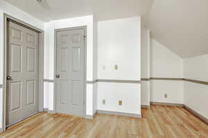 Additional living space featuring light wood-type flooring and lofted ceiling