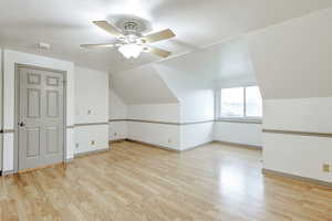 Additional living space featuring lofted ceiling, light wood-style floors, ceiling fan, and a textured ceiling