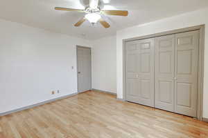 Unfurnished bedroom with a closet, ceiling fan, and light wood finished floors
