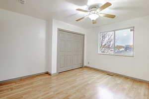 Unfurnished bedroom with light wood-type flooring, a ceiling fan, a closet, and a textured ceiling