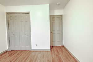 Unfurnished bedroom featuring light wood finished floors and a closet