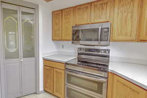 Kitchen featuring stainless steel appliances, light countertops, light flooring, and light brown cabinets