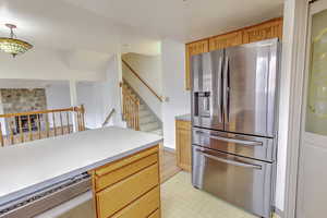Kitchen featuring appliances with stainless steel finishes, light countertops, a fireplace, hanging light fixtures, and light floors