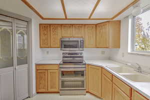 Kitchen with appliances with stainless steel finishes, light countertops, light brown cabinetry, light floors, and a textured ceiling