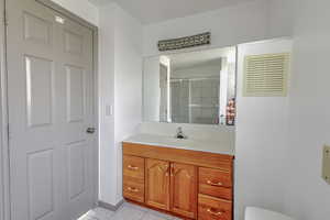 Bathroom featuring vanity, light tile patterned flooring, a stall shower, and a heating unit