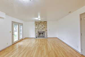 Unfurnished living room featuring a fireplace, a textured ceiling, and light wood finished floors