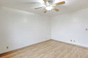 Empty room featuring light wood-type flooring, a ceiling fan, and a textured ceiling