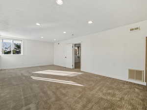 Spare room with a textured ceiling, carpet, and recessed lighting