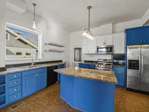 Kitchen featuring blue cabinetry, open shelves, appliances with stainless steel finishes, pendant lighting, and dark stone countertops