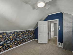 Additional living space with a textured ceiling, lofted ceiling, and carpet flooring