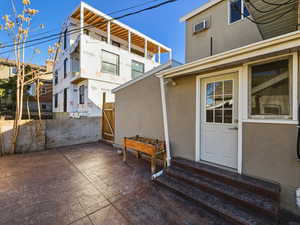 Rear view of house featuring stucco siding, a gate, entry steps, and a wall unit AC