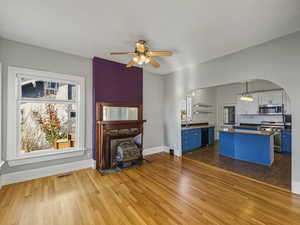 Unfurnished living room with dark wood-type flooring, arched walkways, and plenty of natural light