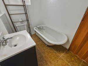Full bathroom featuring a freestanding bath, vanity, and dark tile patterned floors