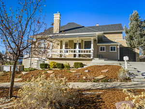 Rear view of house with a chimney, stucco siding, a porch, and roof with shingles