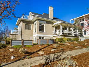 Back of property with stucco siding, a chimney, and roof with shingles