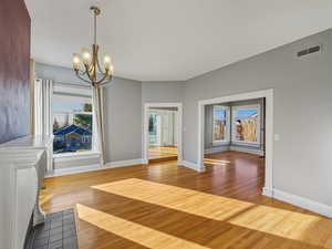 Unfurnished dining area featuring plenty of natural light, light wood-type flooring, and a chandelier