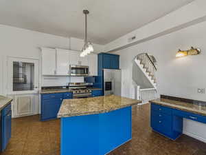 Kitchen with blue cabinetry, dark tile patterned floors, and appliances with stainless steel finishes