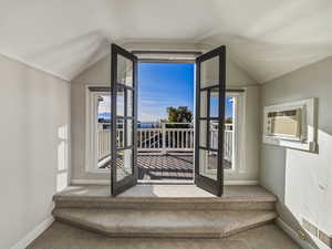 Doorway with carpet, a wall mounted AC, and lofted ceiling