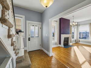 Foyer entrance featuring healthy amount of natural light, light wood finished floors, and a chandelier
