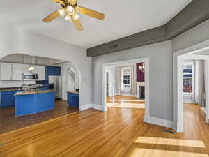 Kitchen with blue cabinetry, dark wood finished floors, hanging light fixtures, a fireplace, and stainless steel appliances