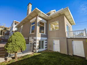 Rear view of property featuring stucco siding, a chimney, and a yard