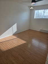 Spare room featuring baseboard heating, dark wood finished floors, and ceiling fan