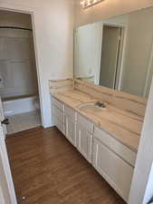 Full bathroom with vanity, dark wood-style flooring, and shower / tub combination