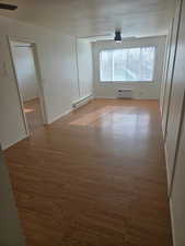 Unfurnished room with a baseboard radiator and wood finished floors