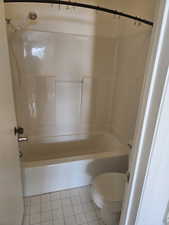 Bathroom with light tile patterned flooring and washtub / shower combination