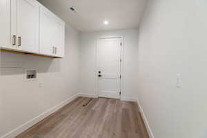 Laundry area featuring light wood finished floors, washer hookup, recessed lighting, and cabinet space