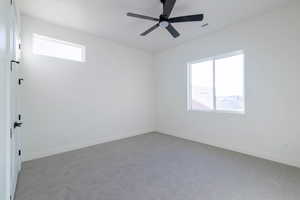 Empty room featuring carpet flooring and a ceiling fan