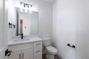 Half bath featuring vanity and dark wood-type flooring